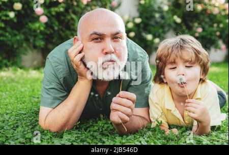 Glücklicher Großvater und Enkel entspannen zusammen. Familien Sommer und Aktivurlaub. Niedlich junge mit Papa spielen im Freien. Glückliche Familie Enkel umarmt seine Stockfoto