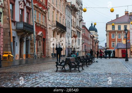LVIV, UKRAINE: Regnerisches Wetter auf dem Marktplatz der Stadt mit Lampfosten und gepflasterten Straßen. Die Altstadt von Lemberg ist Teil des UNESCO-Weltkulturerbes Stockfoto