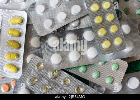 Haufen von verschiedenen Pillen mit Hausarztschrank auf blauem Hintergrund, Schmerzmittel, farbige Pillen, Medizin in Tabletten Stockfoto