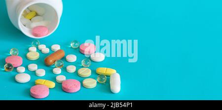 Viele Pillen werden aus einer Medikamentenflasche gegossen. Pillen und Pillen auf blauem Hintergrund. Medizinische Tabletten: Analgetika, Pyretika. Stockfoto