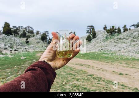 Eine Tasse Tee in der Hand vor dem Hintergrund von Bergen und Städten Stockfoto