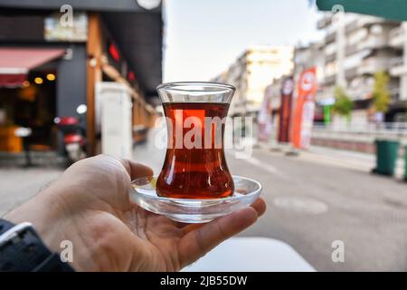 Tasse türkischer Tee in der Hand. Straßen von morgens Antalya, schwarzer Tee. Stockfoto
