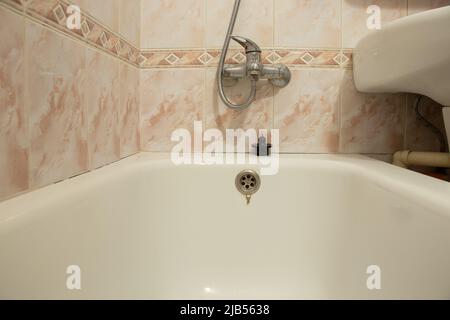 Badezimmer in einem Wohngebäude, Blick von der Badewanne auf die Fliesen und ein Wasserhahn an der Wand Stockfoto