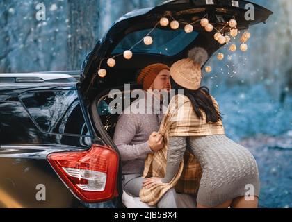 Paar mit Datum und sitzen im Auto in Winterkleidung im Schnee Wald Stockfoto