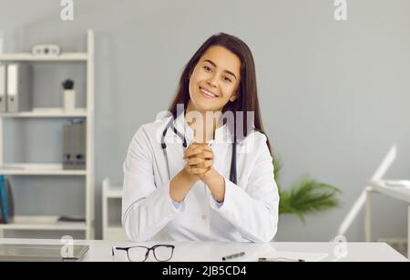 Porträt einer jungen, freundlichen Ärztin, die ihre Patienten über eine Webcam online berät. Stockfoto