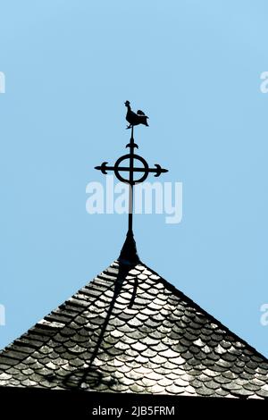 Silhouette eines Vogels auf einer Wetterfahne auf einem Kirchendach vor einem klaren blauen Himmel, Puy de Dome, Auvergne Rhone Alpes, Frankreich Stockfoto