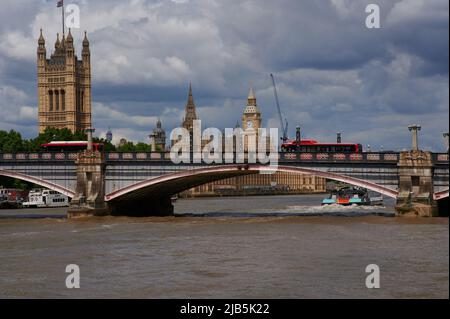 LondonUK - 29. Mai 2022: Blick auf die themse london über die lambeth-Brücke mit vorbeifahrenden roten Bussen in Richtung Parlamentsgebäude Stockfoto