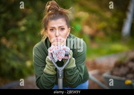 Bild einer müden Frau, die im Garten mit Werkzeugen arbeitet Stockfoto