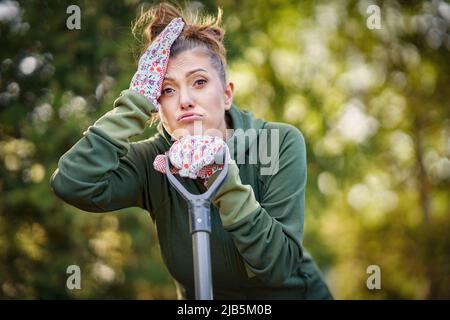 Bild einer müden Frau, die im Garten mit Werkzeugen arbeitet Stockfoto