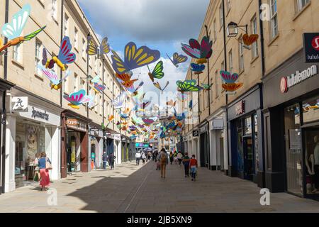 Bunt bunte Schmetterlinge, die in der Luft über den Käufern im Southgate Shopping Centre, City of Bath, Somerset, England, Großbritannien, schweben Stockfoto