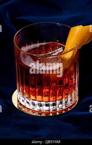 Negroni-Cocktail, italienisches Rezept mit Gin, Bitter und Wermut; garniert mit Orangenschale, in luxuriösem eleganten Hausgetränk Stockfoto