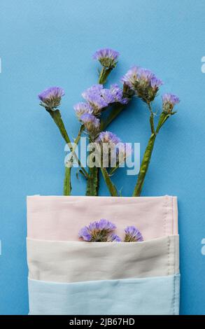 Nahaufnahme von niedlichen blauen Blumen eingewickelt in Serviette auf geservierten Tisch platziert, Dekorationskonzept Stockfoto
