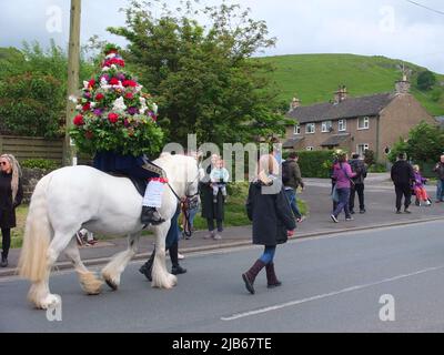 Der König der Castleton Garland mit einem Kranz aus Blumen reitet zu Pferd durch das Dorf während der alten Castleton Garland Ceremony 2022 Stockfoto