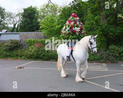 Porträt des Castleton Garland King, der während der alten Castleton Garland Ceremony 2022 eine Kranz aus Blumen zu Pferd trägt Stockfoto