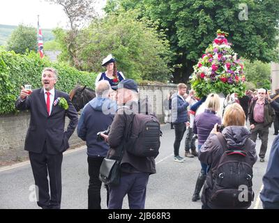 Der König der Castleton Garland mit einem Kranz aus Blumen reitet zu Pferd durch das Dorf während der alten Castleton Garland Ceremony 2022 Stockfoto