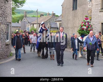 Der König der Castleton Garland mit einem Kranz aus Blumen reitet zu Pferd durch das Dorf während der alten Castleton Garland Ceremony 2022 Stockfoto