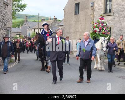 Der König der Castleton Garland mit einem Kranz aus Blumen reitet zu Pferd durch das Dorf während der alten Castleton Garland Ceremony 2022 Stockfoto