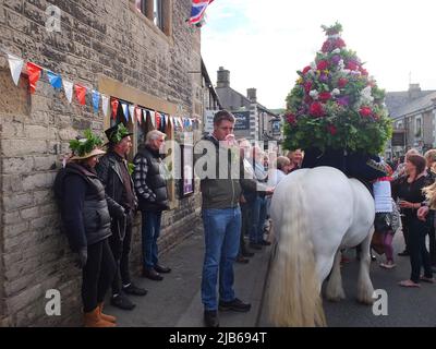 Der König der Castleton Garland mit einem Kranz aus Blumen reitet zu Pferd durch das Dorf während der alten Castleton Garland Ceremony 2022 Stockfoto