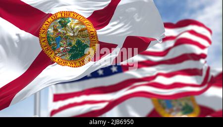 Die Florida-Staatsflagge winkt zusammen mit der Nationalflagge der Vereinigten Staaten von Amerika. Im Hintergrund ist der Himmel klar. Stockfoto