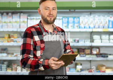 Porträt lächelnder Mitarbeiter, die ein digitales Tablet in einem Teil des Supermarkts benutzen Stockfoto