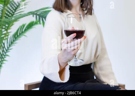 Frau in weißem Kleid trinkt Wein aus einem Weinglas Stockfoto