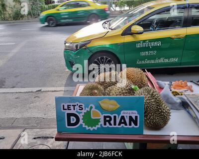 BANGKOK, THAILAND - 3. JUNI 2022 - Durian Früchte verkauft auf der Straße in mit Taxis auf dem Hintergrund Stockfoto