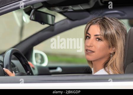 Blonde Frau, die auf dem Fahrersitz eines Autos sitzt Stockfoto
