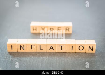 Das Wort Inflation und Hyper im Hintergrund Text auf einem Schiefer mit einem Holzwürfel geschrieben. Stockfoto