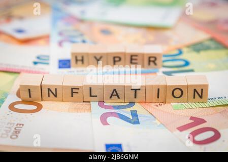 Das Wort Inflation und Hyper im Hintergrund auf Banknoten Euro-Noten mit Holzwürfeln geschrieben Stockfoto