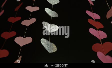 Fliegende rote Papierherzen auf rot dunklem Hintergrund. Valentinstag. Symbol der Liebe. Schöne fliegende rosa Herzen. Alles Gute Zum Valentinstag. Voller Liebe. 4K 4 Stockfoto