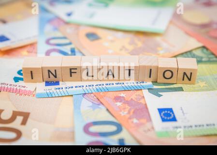 Das Wort Inflation auf Banknoten Euro-Banknoten mit Holzwürfeltext geschrieben Stockfoto