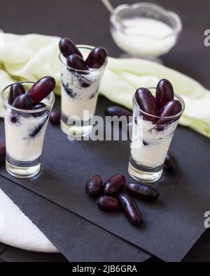 Sommergetränk Lassi, gesundes, süßes, frisches Bio-Getränk aus gefrorenem Joghurt, Dahi oder Quark und roten Trauben. Indischer Frucht-Smoothie auf schwarzem Hintergrund. Stockfoto