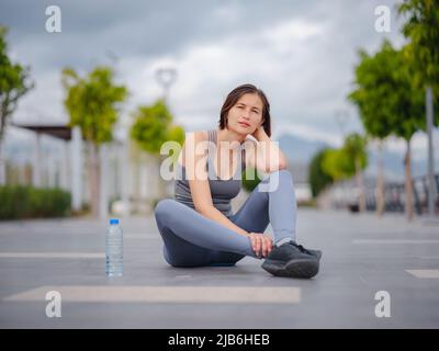 Outdoor-Sport, Workout und Wellness-Konzept. asiatische junge starke, selbstbewusste Frau in sportlicher Kleidung Entspannung nach dem Fitness-Workout in Park. Läuferin, die eine Pause vom Laufsport einnahm. Stockfoto