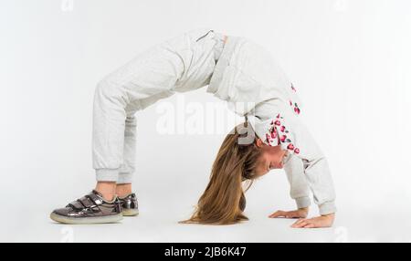 Kleines Mädchen tun Brückenposition auf hellem Hintergrund Stockfoto