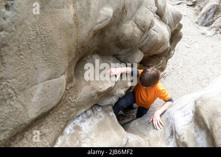 Junge klettert durch die enge Lücke in Bear Gorge, Datvis Khevi, Georgia Stockfoto