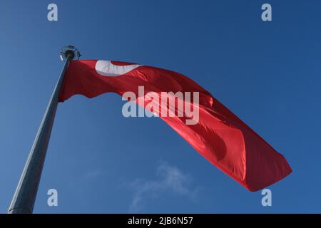 Türkische Flagge von unten. Nationalflagge, bestehend aus einem roten Feld mit einem zentralen weißen Stern und Halbmond. Türkische Flagge winkt am blauen Himmel. Stockfoto