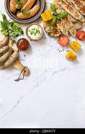 Sommerparty Essen. Grillgerichte. Verschiedene grillwürste mit frischen Kräutern und Gewürzen auf Marmorplatte. Blick von oben. Speicherplatz kopieren. Stockfoto