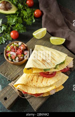 Gesundes Mittagessen. Tortilla-Sandwich, mexikanische Wraps mit gegrilltem Hähnchenfilet und Avocado, serviert mit Guacamole. Stockfoto