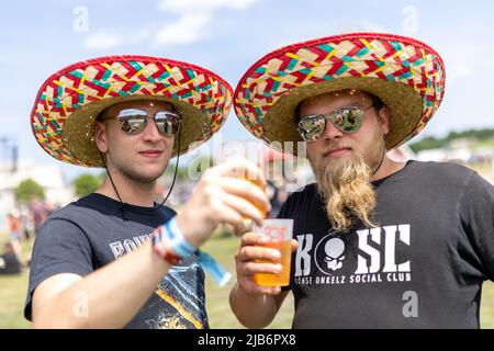 Nürnberg, Deutschland. 03.. Juni 2022. Mit Sombrero und Sonnenbrille warten Benji (l.) und Dominik auf den Beginn des Konzerts beim Open-Air-Festival „Rock im Park“ und genießen einen Drink. Es ist eines der größten Musikfestivals in Bayern. In früheren Jahren kamen bis zu 70.000 Rockfans. Quelle: Daniel Karmann/dpa/Alamy Live News Stockfoto