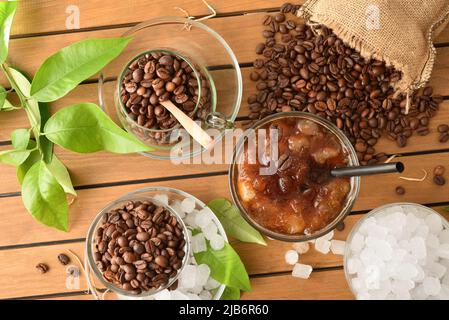 Eiskaffee auf einem Holztisch mit zerkleinertem Eis und Kaffeebohnen um den Tisch herum. Erhöhte Ansicht. Horizontale Zusammensetzung. Stockfoto