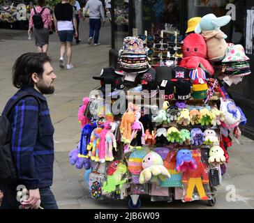 Manchester, Großbritannien, 3.. Juni 2022. Die Leute laufen am Wagen eines Straßenverkäufers vorbei und verkaufen Hüte, Spielzeug und Souvenirs. Tägliches Leben auf den Straßen von Manchester, England, Großbritannien und den Britischen Inseln am zusätzlichen Jubilee Bank Holiday Freitag. Am Freitag, dem 3.. Juni, ist der offizielle Bankfeiertag des Platinum Jubilee, ein zusätzlicher Bankfeiertag zur Feier des 70.-jährigen Bestehens der Königin als Monarch. Quelle: Terry Waller/Alamy Live News Stockfoto