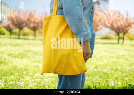 Frau mit gelber Mockup Öko-Tasche auf farbigem Hintergrund. Ökologie oder Umweltschutz Konzept. Stockfoto