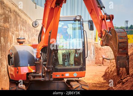 Bagger graben einen Graben zur Stützung von Wand und Straße. Baustellenarbeiten Aushub. Stockfoto