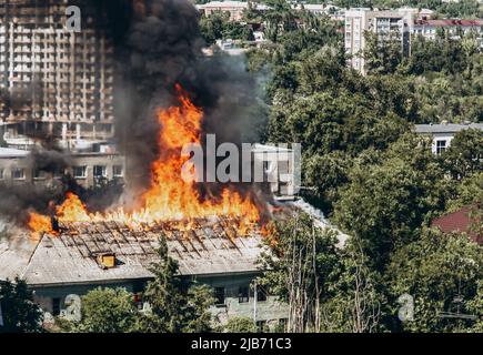 Ein Feuer in einem alten verlassenen Haus, ein Blick aus dem Fenster eines benachbarten Hochhauses. Stockfoto