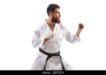 Profilaufnahme eines bärtigen Mannes im Kimono, der Karate auf weißem Hintergrund praktiziert Stockfoto