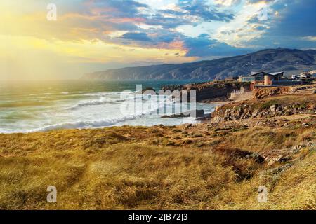 Panoramablick auf die felsige Küste des tobenden Atlantiks nahe Kap Roca im Licht der untergehenden Sonne in Portugal. Gemeinde Sintra, Lissabon Stockfoto