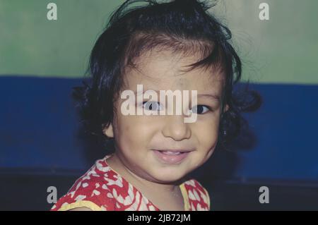 Portrait of adorable Cute Indian glücklich lustige Baby mit Grübchen Alter ein Jahr sechs Monate lächelnd und posiert Blick auf die Kamera. Frohe Kindheit Und Kind Stockfoto
