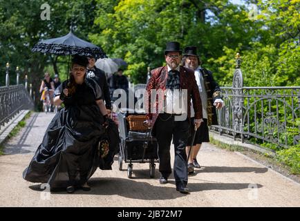 Leipzig, Deutschland. 03.. Juni 2022. Die Teilnehmer in ihren opulenten Kostümen wandern zu Beginn des Wave-Gotik-Treffens (WGT) in Leipzig durch den Clara-Zetkin-Park. Nach einer zweijährigen Pause wegen Corona trifft sich die schwarze Szene zur Ausgabe 29. des Festivals. Rund 200 Bands treten an rund 50 Veranstaltungsorten auf, Zehntausende Fans der schwarzen Szene, Kostümfreaks, dunkle Hippies, Vampir-Fans und Rokoko-Liebhaber verwandeln die Stadt in einen ganz besonderen Kosmos. Quelle: Hendrik Schmidt/dpa/Alamy Live News Stockfoto