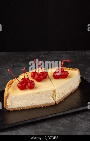 Klassischer Käsekuchen mit Kirschen auf dunklem Hintergrund. Stockfoto