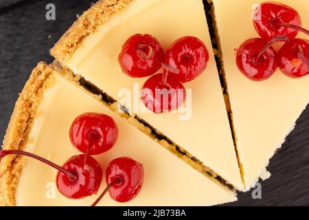 Klassischer Käsekuchen mit Kirschen auf dunklem Hintergrund. Stockfoto